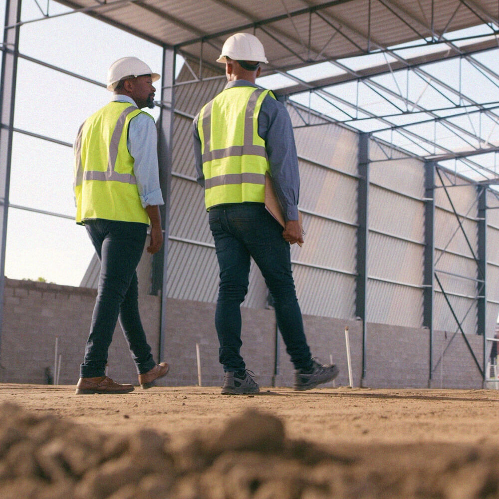Two male property developers assess a commercial site while walking through an empty warehouse space